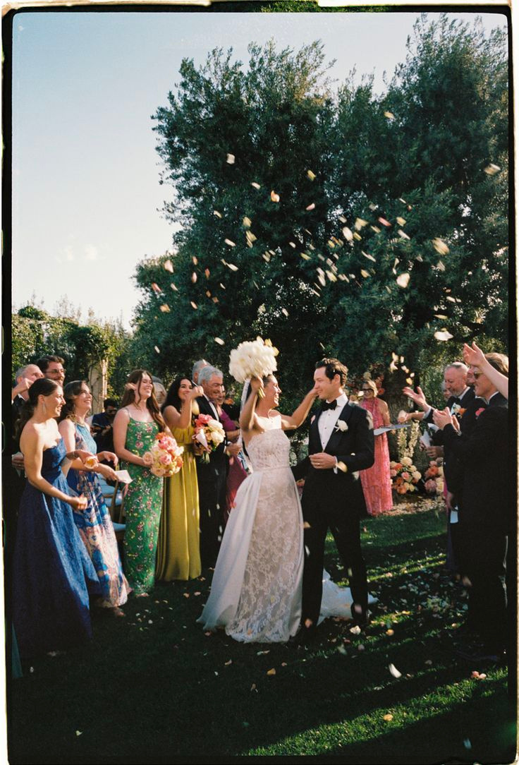 Wedding guests throwing confetti over a newly married couple